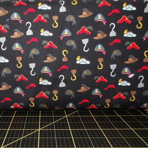 Puede incluir: Tela negra con un patrón repetido de sombreros de pirata, ganchos y espadas. La tela es perfecta para proyectos de manualidades.