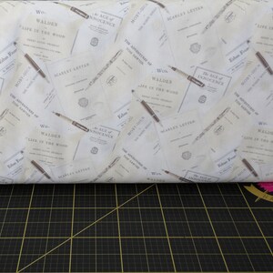 May include: White fabric with a repeating pattern of book covers. The covers feature classic literature titles such as "Moby Dick", "The Scarlet Letter", "The Adventures of Tom Sawyer", "Walden", and "The Age of Innocence".
