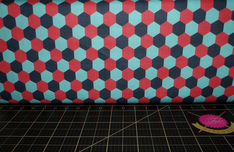 Puede incluir: Una tela con un patr&oacute;n repetido de hex&aacute;gonos rojos, azules y negros. La tela tiene una textura sutil.