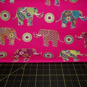 Puede incluir: Una tela rosa vibrante con un patr&oacute;n repetido de elefantes coloridos y dise&ntilde;os circulares. Los elefantes est&aacute;n adornados con intrincados patrones en tonos verdes, azules, naranjas y morados.