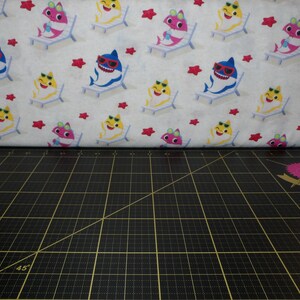 Ressorts créatifs. Bébé requin. Tissu beige clair avec des étoiles de mer - Tissu avec des bébés requins