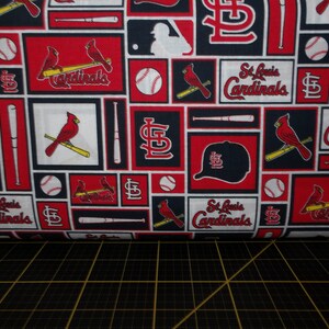 May include: Red, white, and blue fabric with a repeating pattern of baseball bats, baseballs, cardinals, and the words "St. Louis Cardinals".