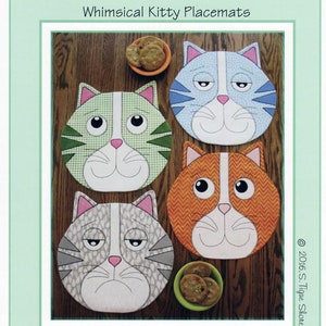 Może przedstawiać: Cztery kapryśne podkładki pod talerze w kształcie kotów o różnych kolorach futra i wyrażeniach twarzy. Podkładki są okrągłe i mają biały pasek w środku twarzy. Tekst "Kippers Whimsical Kitty Placemats" znajduje się w górnej części obrazu. Tekst "ST-1704" znajduje się w prawym górnym rogu. Tekst "Susie C Shore Designs" znajduje się w dolnej części obrazu.
