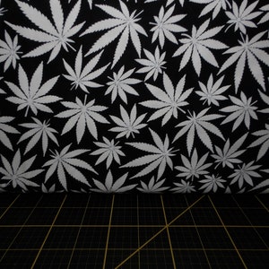 Puede incluir: Patrón de hojas de marihuana blancas sobre un fondo de tela negro.