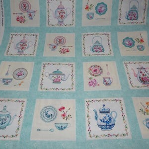 May include: A teal fabric with a repeating pattern of teapots, teacups, and saucers. The teacups and saucers are decorated with floral designs. The teapots are decorated with floral designs and have a lid.
