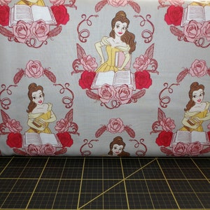 May include: A gray fabric with a repeating pattern of Belle from Beauty and the Beast holding a book. The pattern also includes red and pink roses.