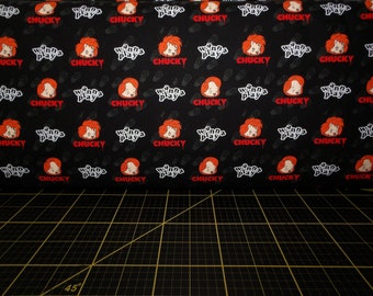 May include: Black fabric with a repeating pattern of a red-haired girl's face with the text "Wanna Play" and "Chucky" in red.