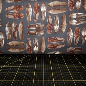 Puede incluir: Una tela gris con un patrón repetido de zapatos de cuero marrón. Los zapatos tienen un diseño de punta de ala y están dispuestos en un patrón escalonado.
