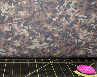 Könnte beinhalten: Braunes, beiges und schwarzes digitales Tarnmustergewebe. Der Stoff ist über eine schwarze Schneidematte mit einem rosa-weißen Logo gefaltet, auf dem "Tula Hardow" in weiß steht.