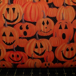 May include: Orange fabric with a repeating pattern of smiling jack-o'-lanterns. The pumpkins have various facial expressions and are set against a black background with white polka dots. A festive Halloween theme.