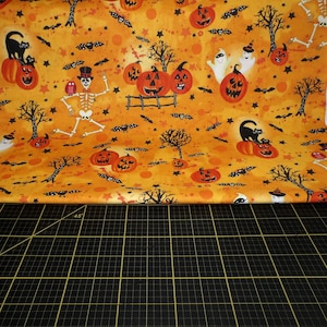 Fabricación de telas. Brillo de medianoche. Toile de luna naranja claro: esqueletos, calabazas y fantasmas de Halloween.