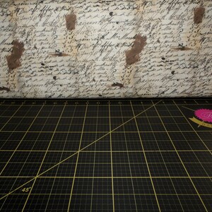 May include: A black cutting mat with a grid pattern and a diagonal line marked with 45 degrees. The mat has a pink and white label that says "Tula Pink" in a cursive font.