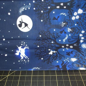 Pode incluir: Tecido azul com um desenho de silhueta branca de um unicórnio, uma fada e uma lua. O tecido tem um padrão de estrelas brancas.