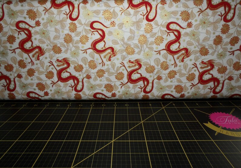May include: White fabric with a repeating pattern of red dragons and gold floral designs.