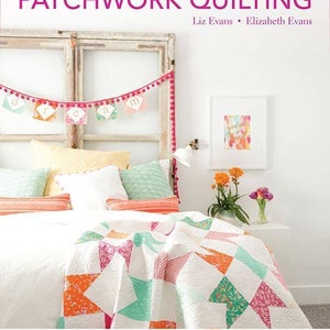 Può includere: Un libro intitolato "The Simple Simon Guide to Patchwork Quilting" di Liz Evans ed Elizabeth Evans. La copertina del libro presenta un letto bianco con una trapunta patchwork in tonalità di rosa, arancio e verde. Il testo "Two Girls, Eight Blocks, 24 Blissful Patchwork Projects" e "Includes 8 Complete Quilt Designs" è stampato nella parte inferiore della copertina.