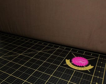 Puede incluir: Una estera de corte negra con un patrón de cuadrícula y un logotipo rosa y dorado que dice "Club Pink Hardware".