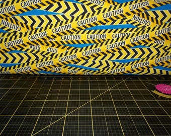 Peut inclure: Ruban de signalisation jaune et noir avec le mot "CAUTION" et des flèches imprimées dessus. Le ruban est plié et l'arrière-plan est un tapis de coupe noir.
