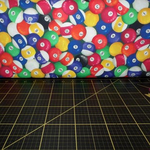 May include: A colorful fabric with a repeating pattern of billiard balls. The balls are red, yellow, blue, green, and white with black numbers on them.