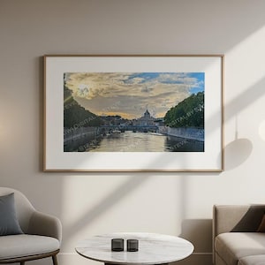 May include: A framed print of a scenic landscape featuring a river, bridge, and a domed building under a cloudy sky. The artwork is displayed on a neutral-colored wall, complemented by a modern interior design.