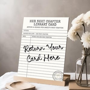 May include: A white rectangular sign featuring black text that reads Her Next Chapter Library Card, Advice & Wishes For Emily's Next Chapter, and Return Your Card Here. The sign includes lines for author, date, and words, with a circular stamp.