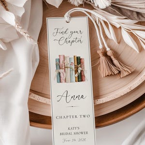 Op de afbeelding: Een rechthoekige bladwijzer met de tekst "Find your Chapter" en een aquarel illustratie van boeken. De bladwijzer bevat de naam "Anna", "Chapter Two" en details voor een bruidsfeest.