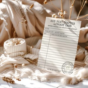 A single library card advice template rests on neutral textured fabric next to a small dish and dried florals.