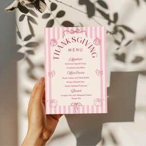 Pu&ograve; includere: Un biglietto del menu del Ringraziamento a righe rosa e bianche con la parola "Thanksgiving" in alto. Il menu include antipasti, piatti principali e dessert, con illustrazioni di zucche e fiocchi.