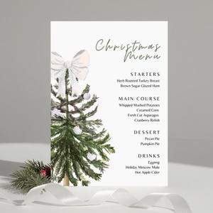May include: A Christmas menu card with a watercolor illustration of a decorated Christmas tree and a white bow. The menu lists starters, main courses, desserts, and drinks, including herb-roasted turkey breast and eggnog.