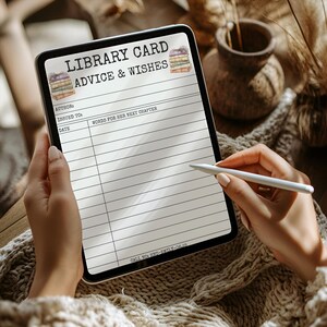 May include: A digital tablet displaying a "LIBRARY CARD ADVICE & WISHES" template. The template includes fields for author, recipient, date, and space for "WORDS FOR HER NEXT CHAPTER." The tablet is held by a person, with a stylus poised above the screen.