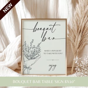 A gold-framed table sign reading Bouquet Bar Make a bouquet to take with you with a floral illustration.