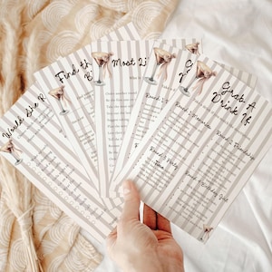 May include: A hand holds a stack of party game cards with a cocktail illustration. The cards have a striped background and include phrases like "Would She R", "Find the B", and "Grab A Drink If".