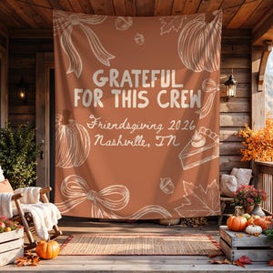 K&ouml;nnte beinhalten: Ein rechteckiger Wandbehang aus Stoff in gebranntem Orange mit wei&szlig;en Linienzeichnungen von K&uuml;rbissen, Schleifen, Eicheln und Bl&auml;ttern. Der Text lautet: GRATEFUL FOR THIS CREW, Friendsgiving 2026, Nashville, TN. Das Design ist auf Stoff gedruckt.
