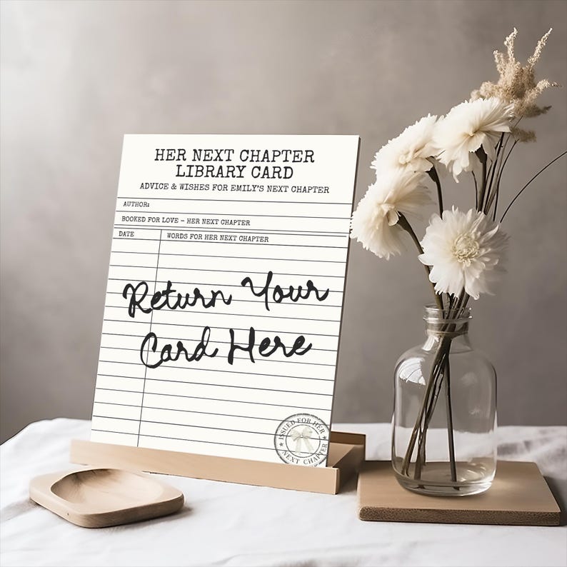 May include: A white rectangular sign featuring black text that reads Her Next Chapter Library Card, Advice & Wishes For Emily's Next Chapter, and Return Your Card Here. The sign includes lines for author, date, and words, with a circular stamp.