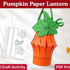 Può includere: Una lanterna di carta a forma di zucca con un corpo cilindrico arancione dotato di fessure verticali, sormontato da foglie verdi e un gambo. Accanto si trovano due fogli di carta bianca con modelli a linee nere per la lanterna.