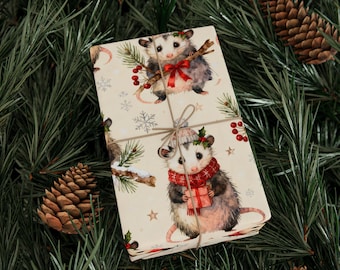 Könnte beinhalten: Ein verpacktes Geschenk mit Opossum-Illustrationen, die Winteraccessoires tragen. Das Geschenkpapier zeigt Opossums, die Zweige mit Beeren halten und Schals und Hüte tragen. Das Geschenk ist mit Bindfaden gebunden und vor einem Hintergrund aus Tannennadeln und Tannenzapfen platziert.