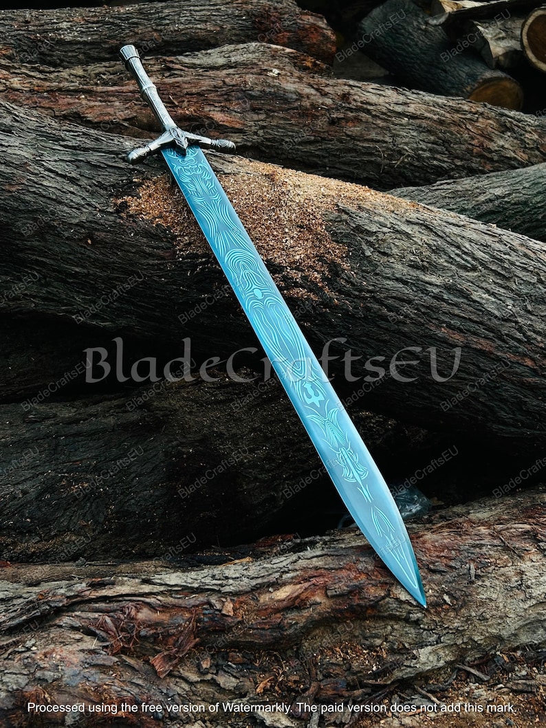 K&ouml;nnte beinhalten: Ein gro&szlig;es, verziertes Schwert mit einer blauen Klinge und einem silbernen Griff liegt auf einem Holzstapel. Die Klinge weist ein detailliertes Muster auf. Der Text "BladeCraftsEU" ist im Bild sichtbar.