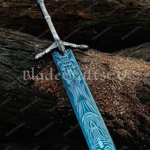 K&ouml;nnte beinhalten: Ein dekoratives Schwert mit einer blauen Klinge und aufwendigen wei&szlig;en Designs. Der Knauf und der Parier sind silberfarben. Das Schwert wird auf einer strukturierten, braunen Oberfl&auml;che pr&auml;sentiert. Der Text "BladeCraftsEU" ist sichtbar.