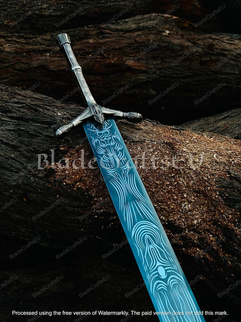 K&ouml;nnte beinhalten: Ein dekoratives Schwert mit einer blauen Klinge und aufwendigen wei&szlig;en Designs. Der Knauf und der Parier sind silberfarben. Das Schwert wird auf einer strukturierten, braunen Oberfl&auml;che pr&auml;sentiert. Der Text "BladeCraftsEU" ist sichtbar.