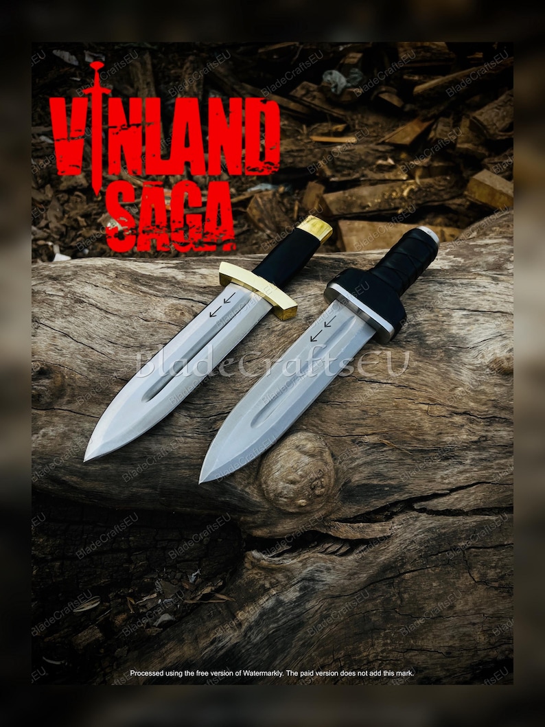 Puede incluir: Dos dagas plateadas con mangos negros y detalles dorados, expuestas sobre una superficie de madera envejecida. Las hojas tienen marcas de flechas. El texto "VINLAND SAGA" est&aacute; en rojo sobre las dagas.