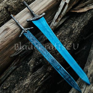 K&ouml;nnte beinhalten: Zwei verzierte Schwerter mit blauen Klingen und detaillierten silbernen Griffen liegen auf einer strukturierten Holzoberfl&auml;che. Die Klingen weisen aufwendige ge&auml;tzte Muster auf. Ein Beispiel f&uuml;r Handwerkskunst.