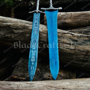 K&ouml;nnte beinhalten: Zwei blaue Fantasy-Schwerter mit verzierten silbernen Griffen und Klingen. Ein Schwert hat ein eingraviertes Design. Die Schwerter werden auf einem Bett aus Holzst&auml;mmen pr&auml;sentiert. Der Text "BladeCraftsEU" ist enthalten.