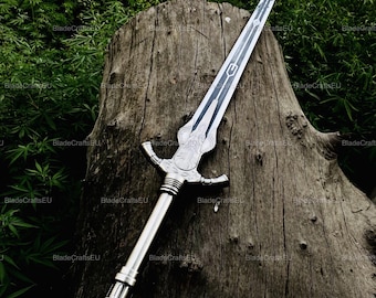 May include: A silver sword with a detailed hilt and a long, pointed blade. The blade has a dark, etched design. The sword is displayed on a weathered, textured tree stump against a backdrop of green foliage. The sword's handle has a cross-guard design.