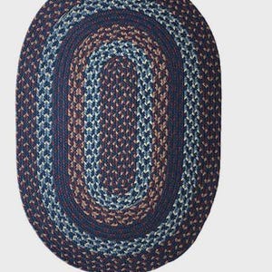 May include: Oval braided rug in shades of navy blue, brown, and light blue. The rug features a concentric design with a dark blue border. This durable rug is suitable for entryways, kitchens, or bedrooms.