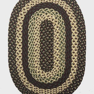 May include: Oval braided rug in shades of dark green, brown, and beige. The rug features a concentric oval design, with a dark brown border and a mix of green and beige in the center. The rug is made of woven material.