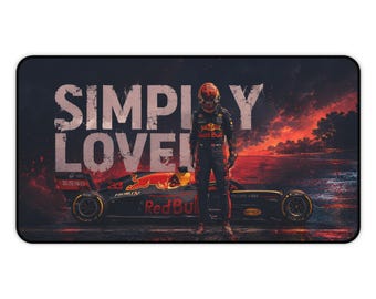 Peut inclure: Un tapis de bureau rectangulaire représentant une voiture de course de Formule 1 et un pilote en combinaison debout devant. Le texte SIMPLY LOVELY est imprimé en grandes lettres blanches. L'arrière-plan montre un coucher de soleil ardent.