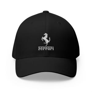 Op de afbeelding: Zwarte baseballcap met het witte Ferrari-logo. Het logo toont een steigerend paard en de merknaam. De cap heeft een gebogen klep en een gestructureerde pasvorm, geschikt voor dagelijks gebruik.