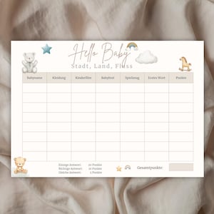 Könnte beinhalten: Eine cremefarbene Babyparty-Spielkarte mit den Worten "Hello Baby" und "Stadt, Land, Fluss" in handschriftlicher Schrift. Die Karte zeigt Illustrationen eines Teddybären, eines Sterns, eines Regenbogens, einer Wolke und eines Schaukelpferds.