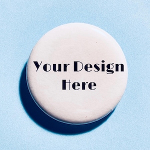 May include: A circular white button featuring the black text Your Design Here printed in the centre. The button has a smooth, matte surface and a clean, rounded edge, presenting a blank canvas for custom graphics or personalised artwork.