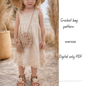 Op de afbeelding: Een kind in een beige jurk en sandalen met bloemenaccenten draagt een gehaakte tas met een kwast. De tas heeft een rond, gedetailleerd ontwerp. Tekst rechts luidt "Crochet bag pattern, oversize, Digital only PDF."