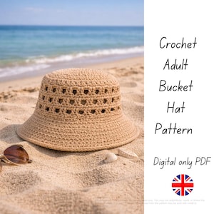 May include: A beige crochet bucket hat with a wide brim sits on a sandy beach. The hat has a series of decorative openings around the crown. Sunglasses and seashells are next to the hat. Text on the right reads "Crochet Adult Bucket Hat Pattern".